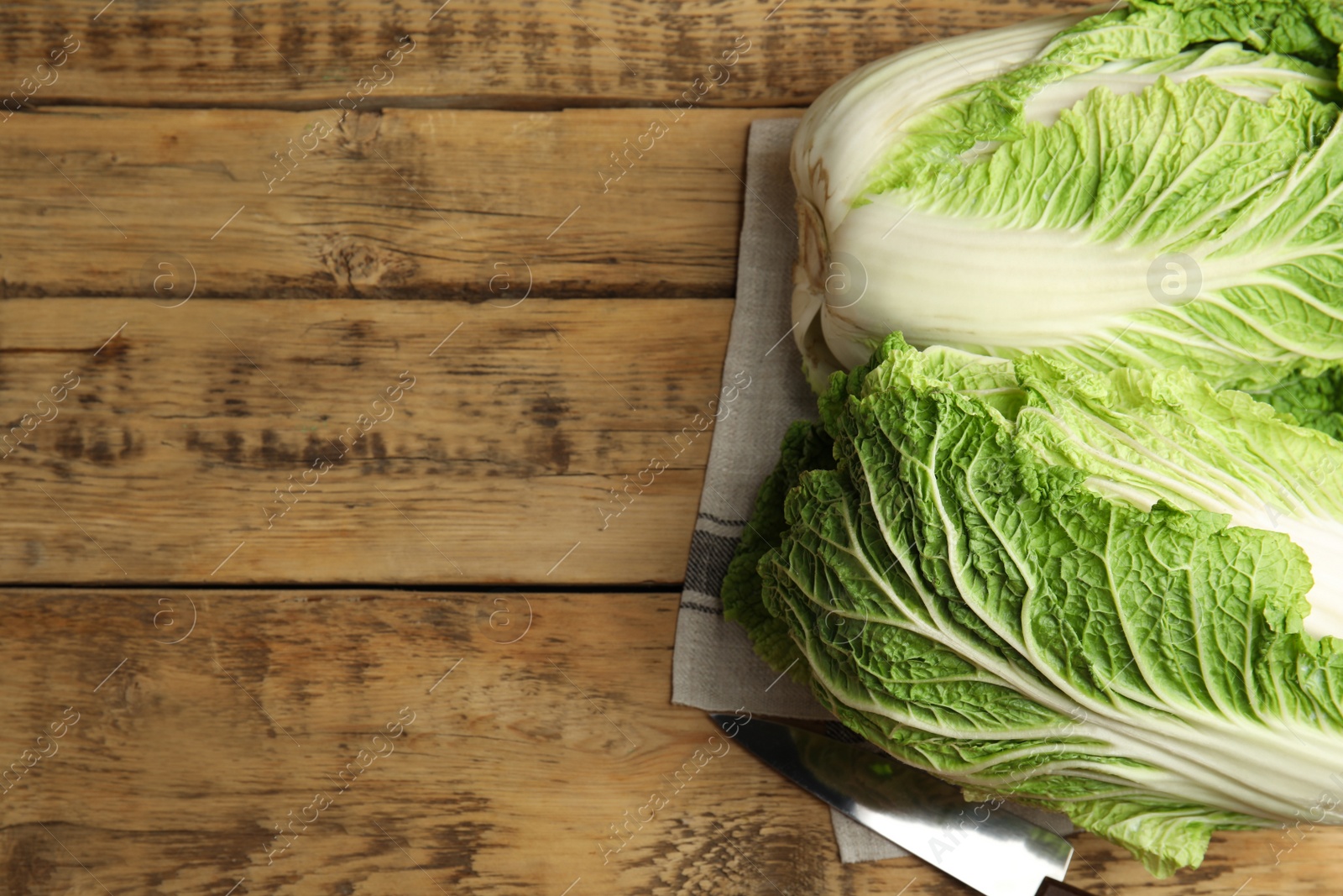 Photo of Fresh ripe Chinese cabbages and knife on wooden table, top view. Space for text