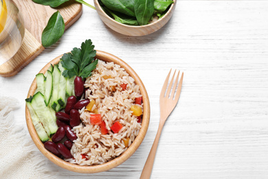 Photo of Delicious rice with beans served on white wooden table, flat lay