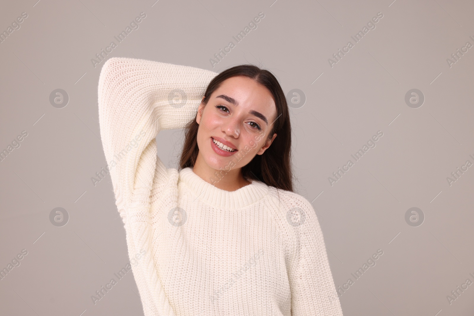 Photo of Beautiful young woman in stylish warm sweater on grey background