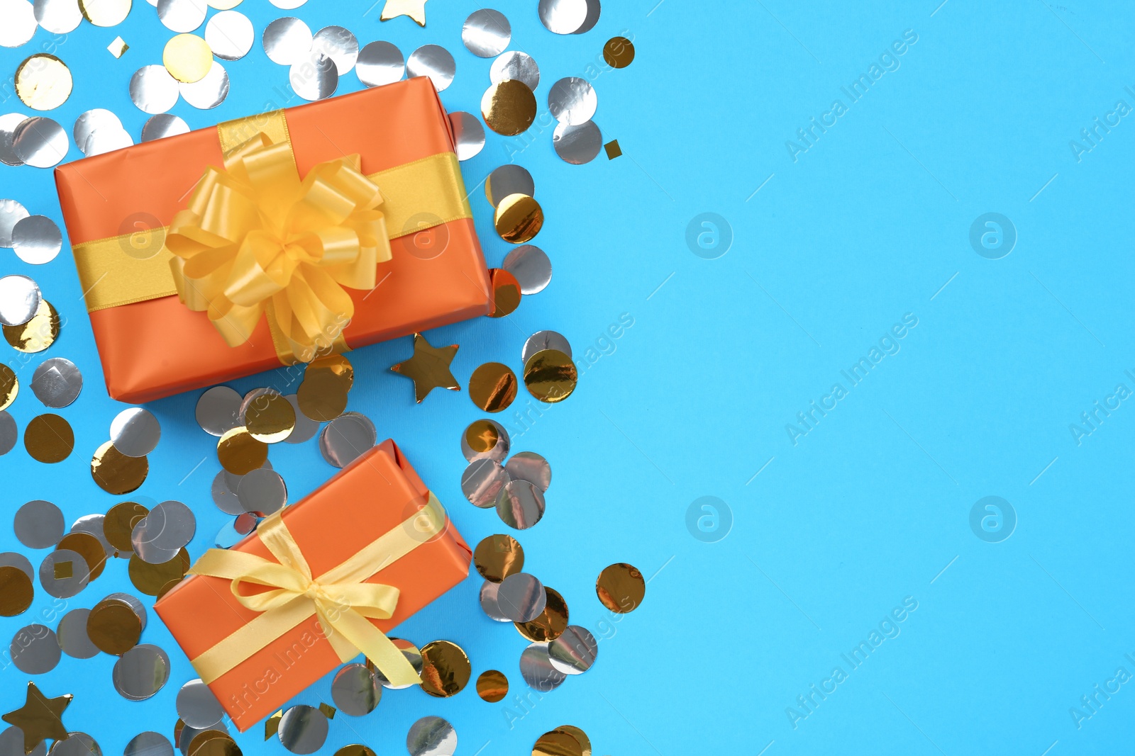 Photo of Gift boxes and shiny confetti on light blue background, flat lay. Space for text