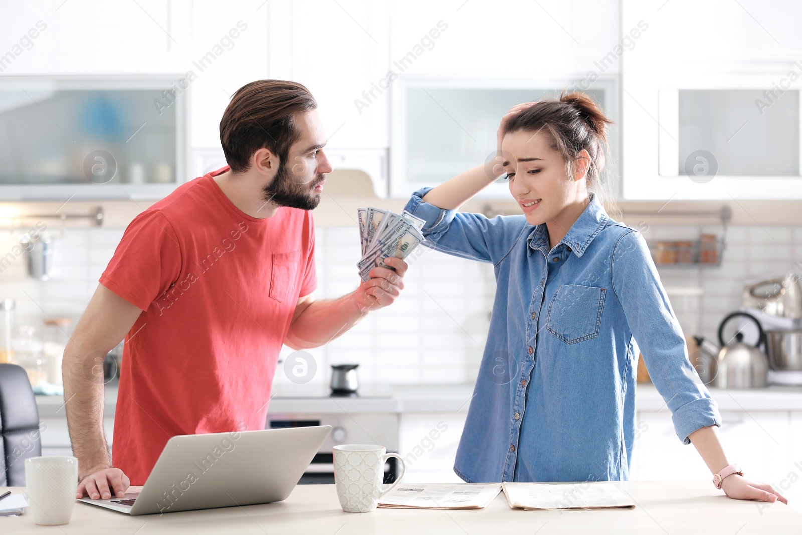 Photo of Young couple having argument about family budget in kitchen