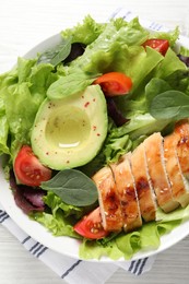 Photo of Delicious salad with chicken, cherry tomato and avocado on table, top view