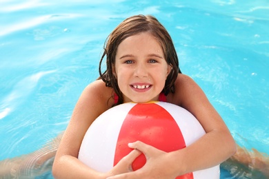 Photo of Happy cute girl with inflatable ball in swimming pool