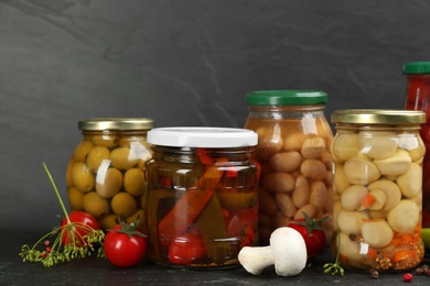 Photo of Jars of pickled vegetables on grey background