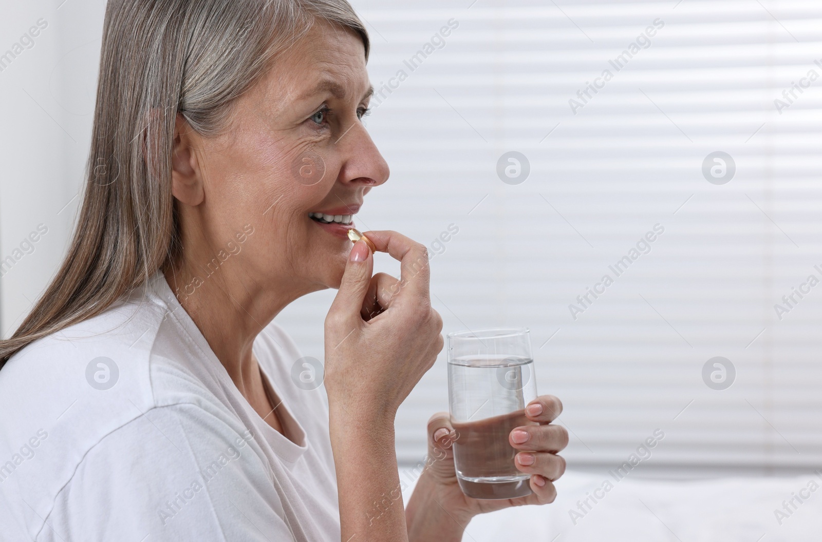 Photo of Beautiful woman taking vitamin pill at home