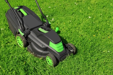 Photo of Cutting green grass with lawn mower in garden
