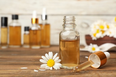 Photo of Composition with bottle of chamomile essential oil on table. Space for text