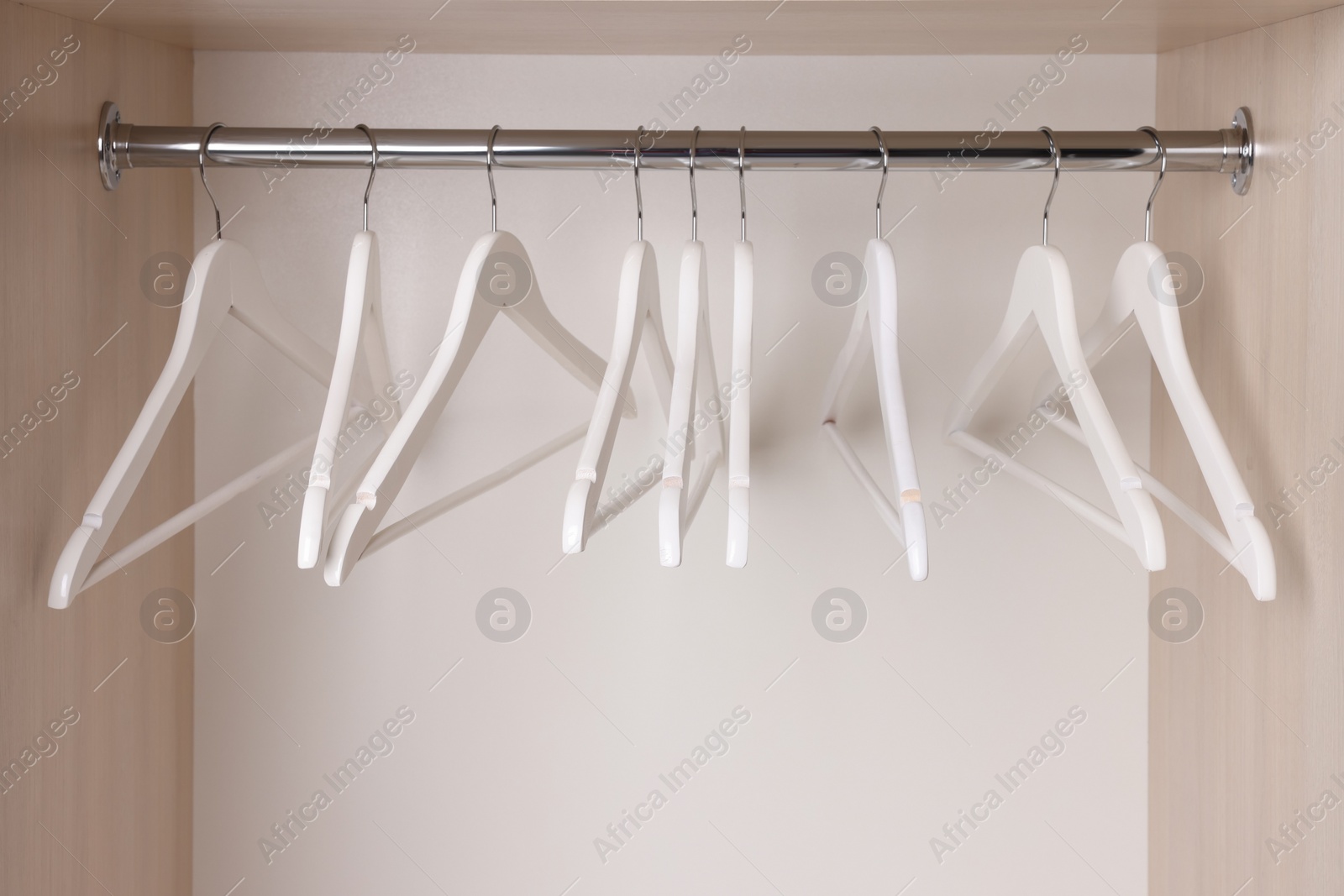 Photo of Setwooden clothes hangers on wardrobe rail