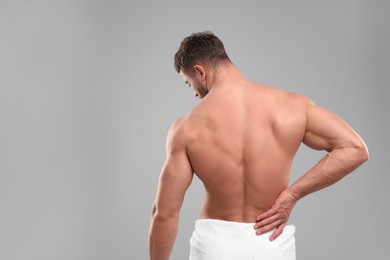 Photo of Man suffering from back pain on grey background, back view. Space for text