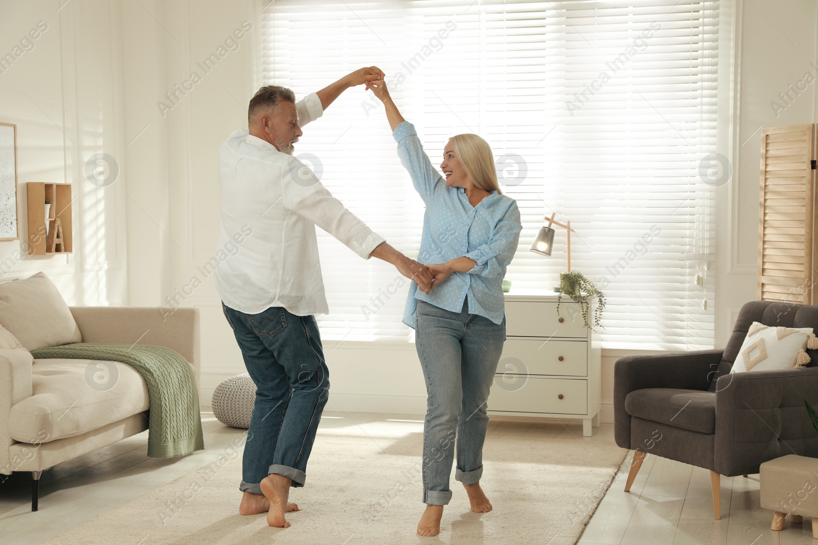 Photo of Happy senior couple dancing together in living room