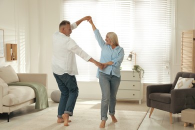 Happy senior couple dancing together in living room