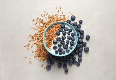 Photo of Bowl of yogurt with granola and blueberries on grey marble table, flat lay