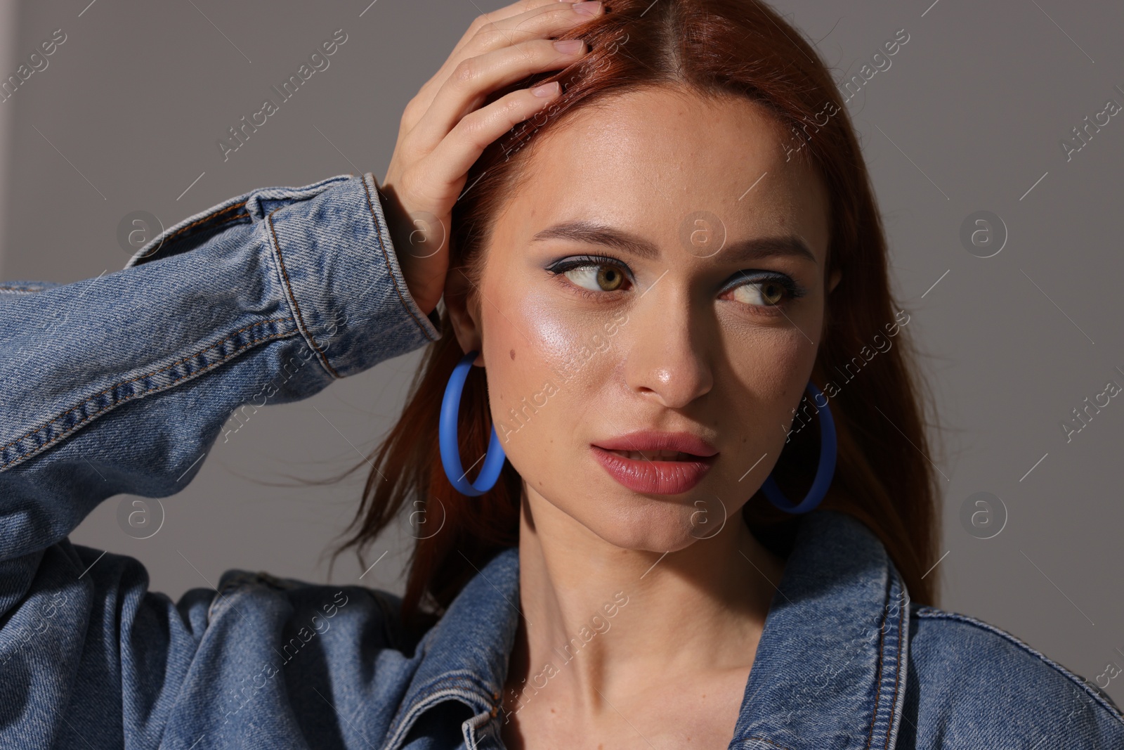 Photo of Beautiful young woman in denim jacket on gray background