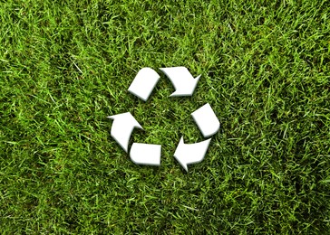 Green grass and illustration of recycling symbol, top view