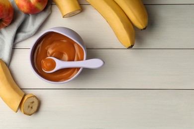 Healthy baby food in bowl and fresh fruits on white wooden table, flat lay. Space for text