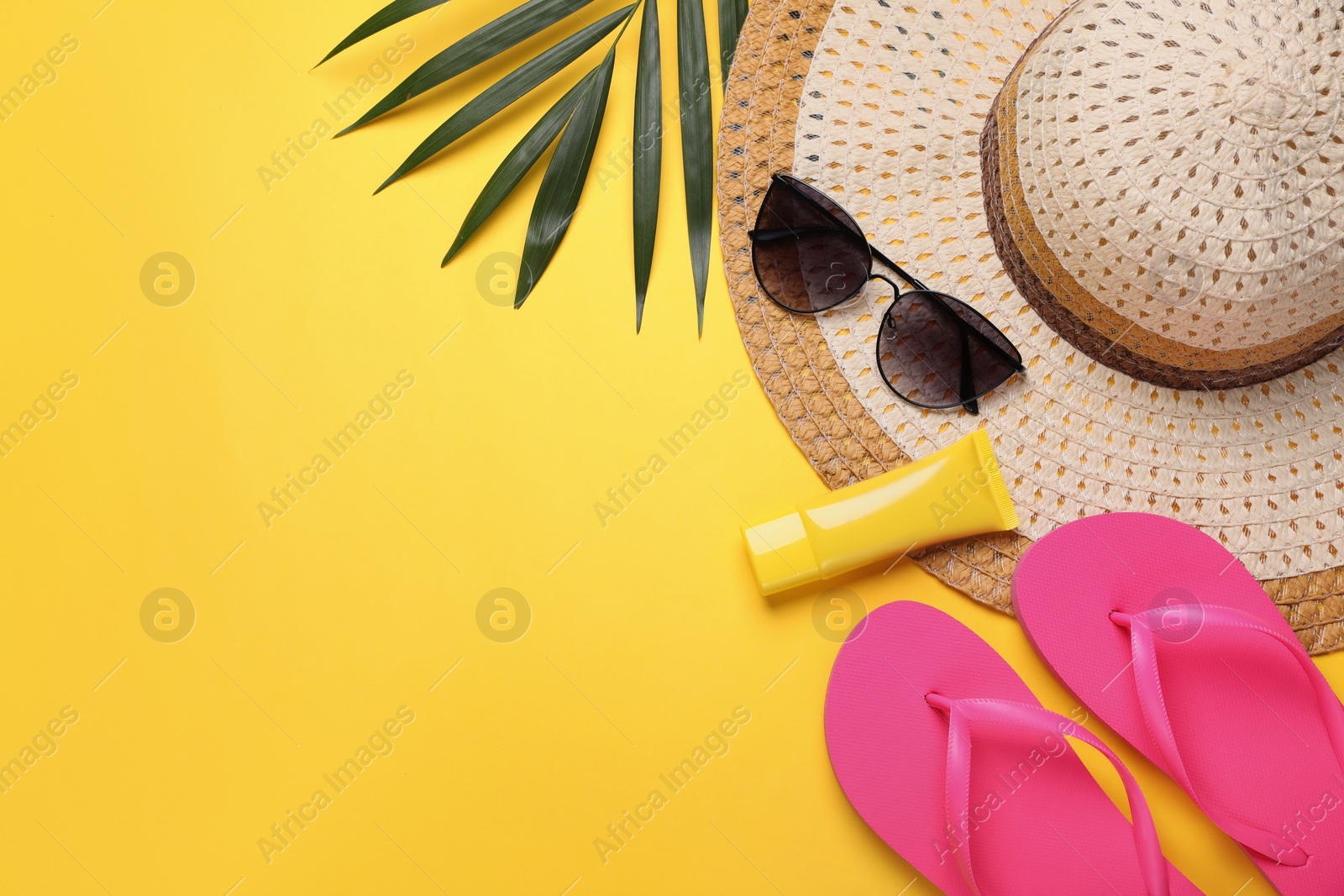 Photo of Flat lay composition with sunscreen and beach accessories on yellow background. Space for text