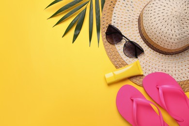 Flat lay composition with sunscreen and beach accessories on yellow background. Space for text