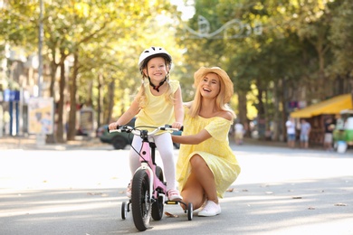 Photo of Mother teaching daughter to ride bicycle on street