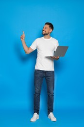 Photo of Happy man with laptop on light blue background