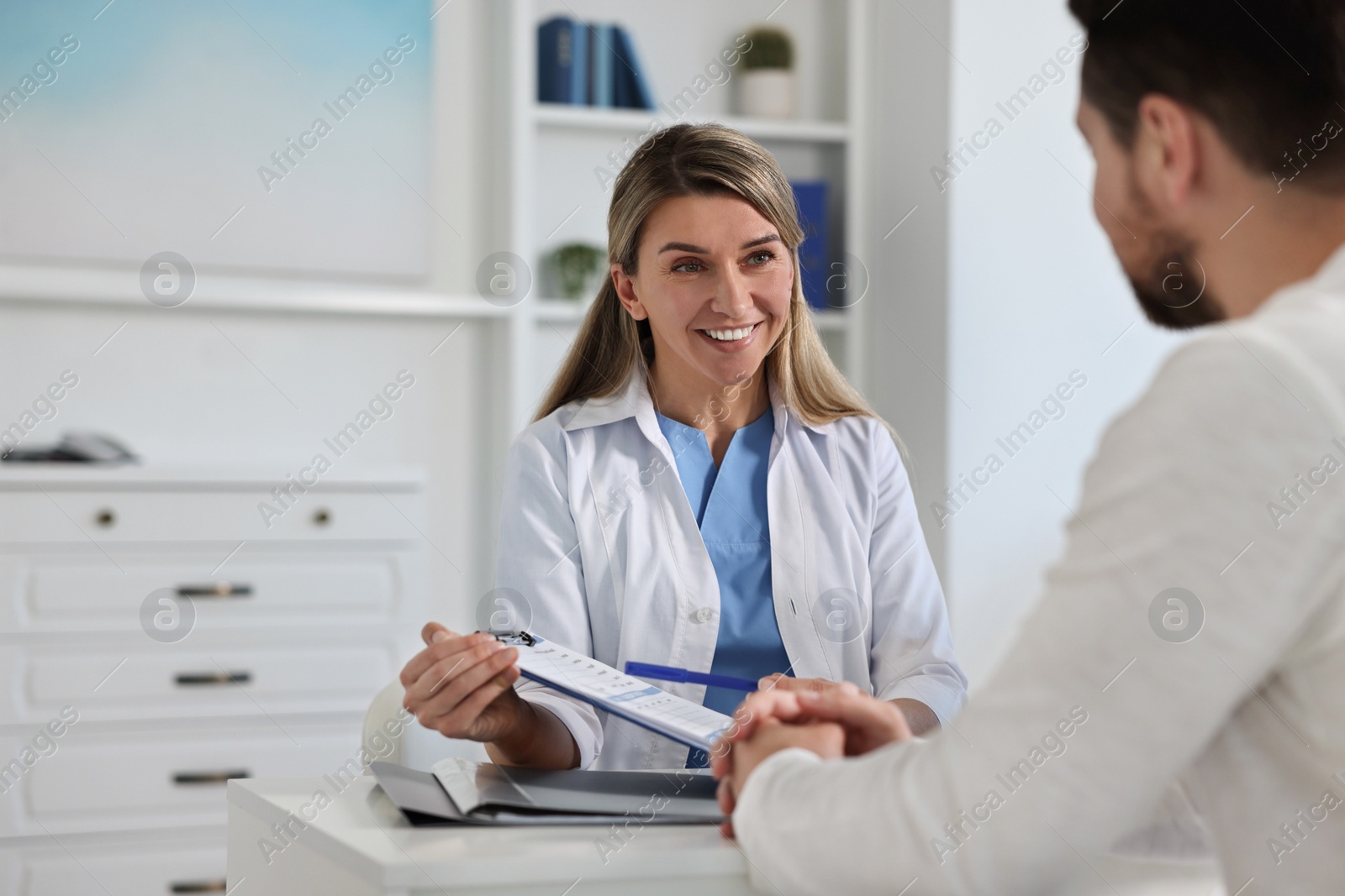 Photo of Professional doctor working with patient at white table in hospital