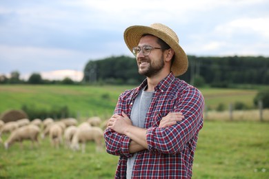 Photo of Portrait of smiling man with crossed arms on pasture at farm