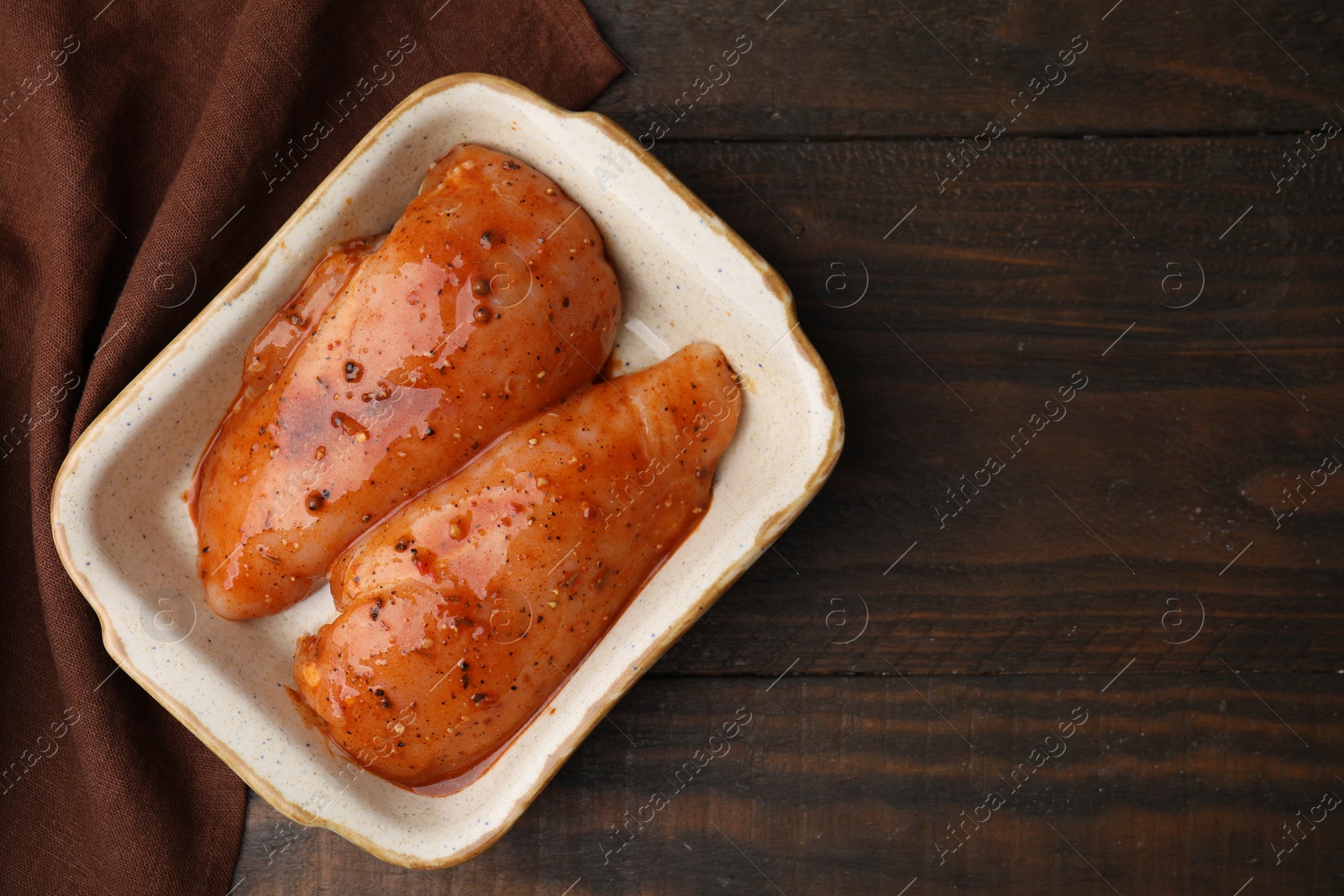 Photo of Raw marinated chicken fillets on wooden table, top view. Space for text