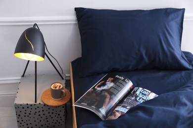 Photo of Open magazine on bed with stylish silky linens