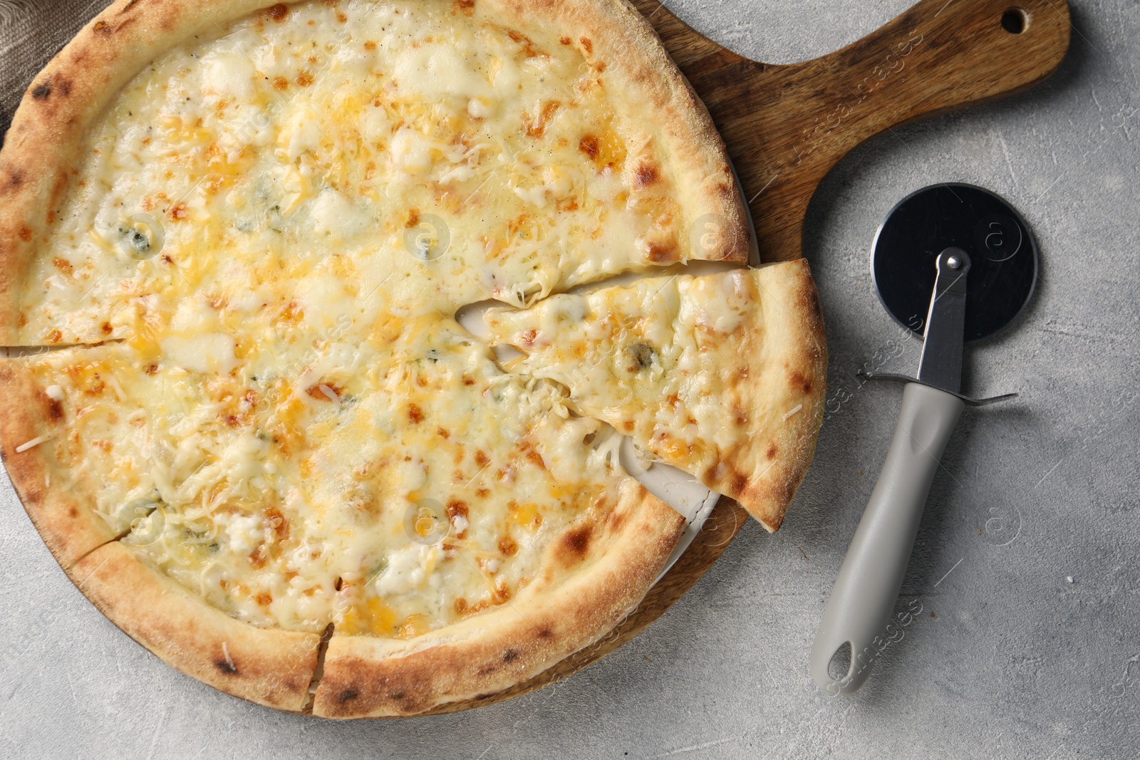 Photo of Delicious cheese pizza and cutter on light grey table, flat lay