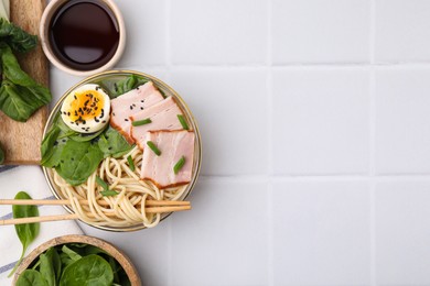 Delicious ramen with meat served on white tiled table, flat lay and space for text. Noodle soup