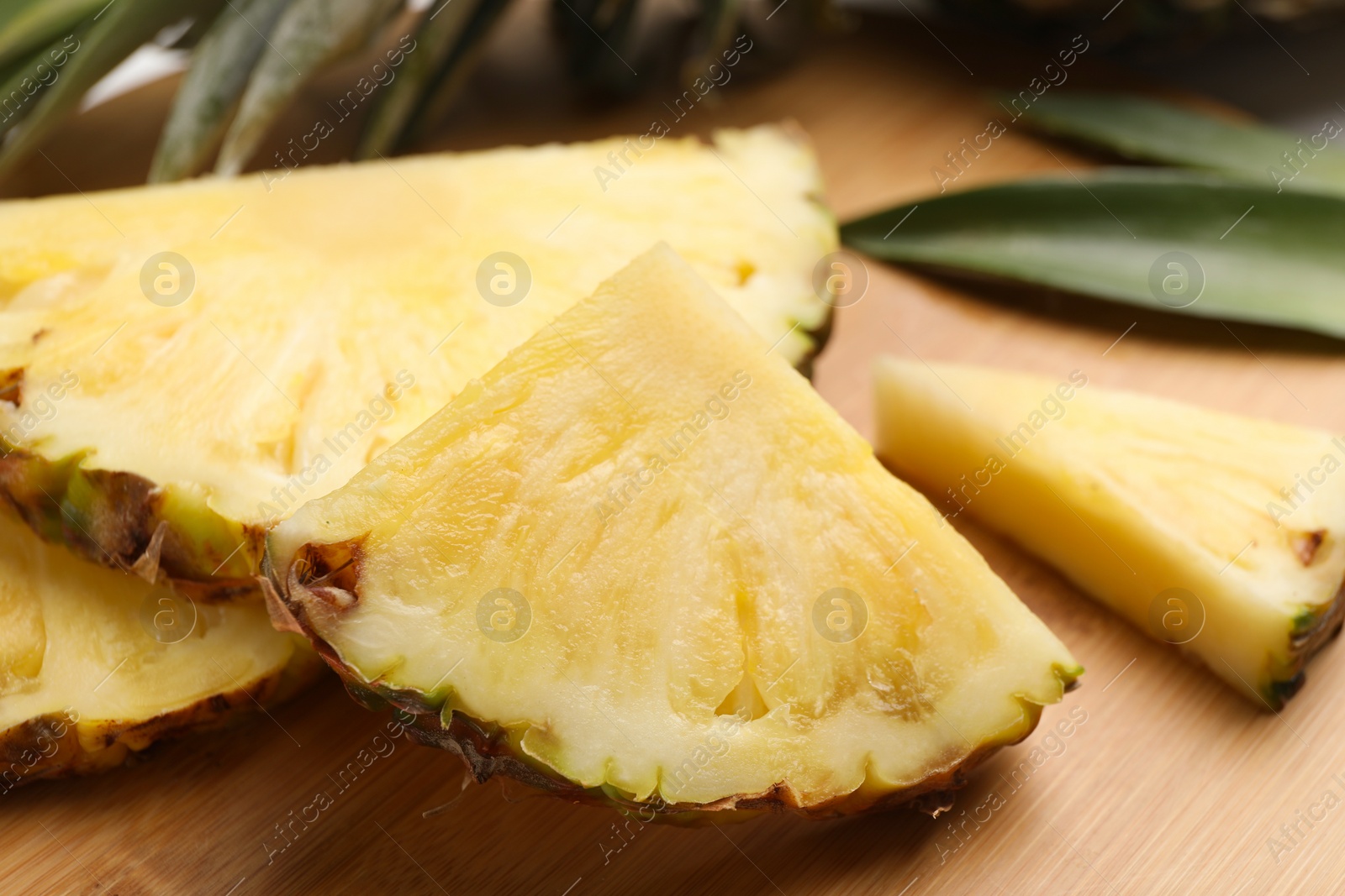 Photo of Slices of ripe juicy pineapple on wooden board, closeup