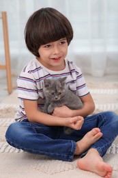 Cute little boy with kitten on floor at home. Childhood pet