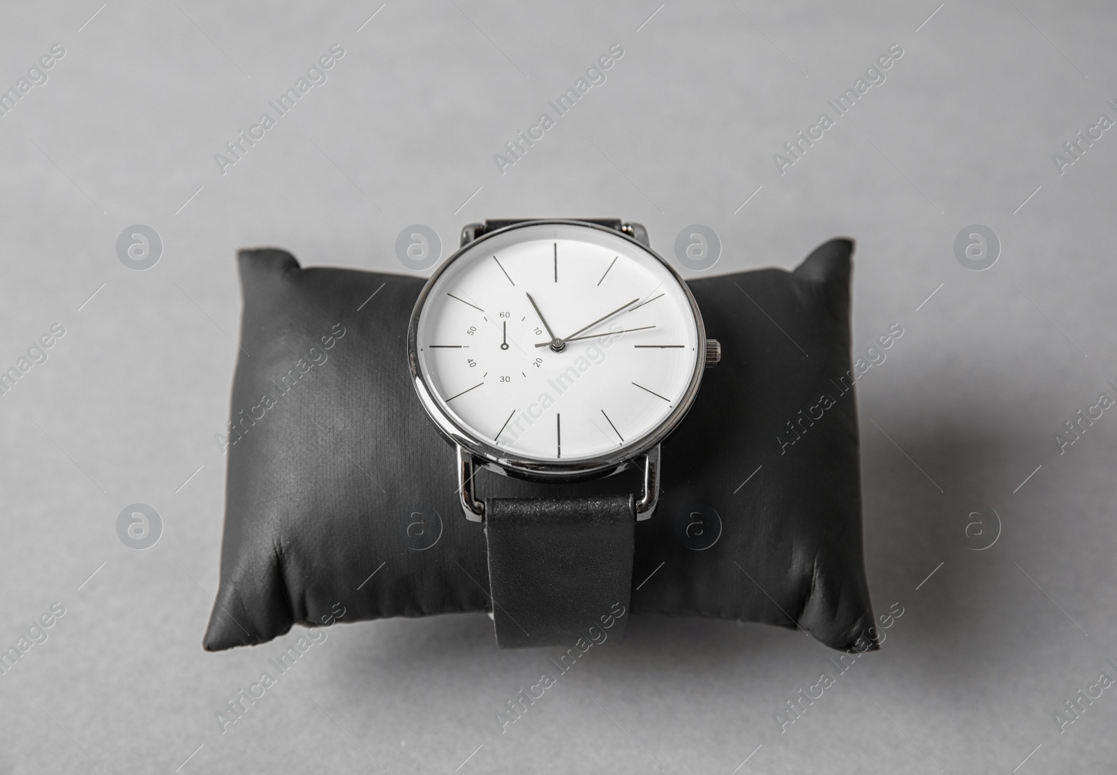 Photo of Small decorative pillow with stylish wrist watch on gray background. Fashion accessory