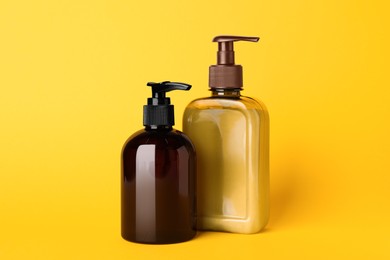 Photo of Different bottles of shampoo on yellow background