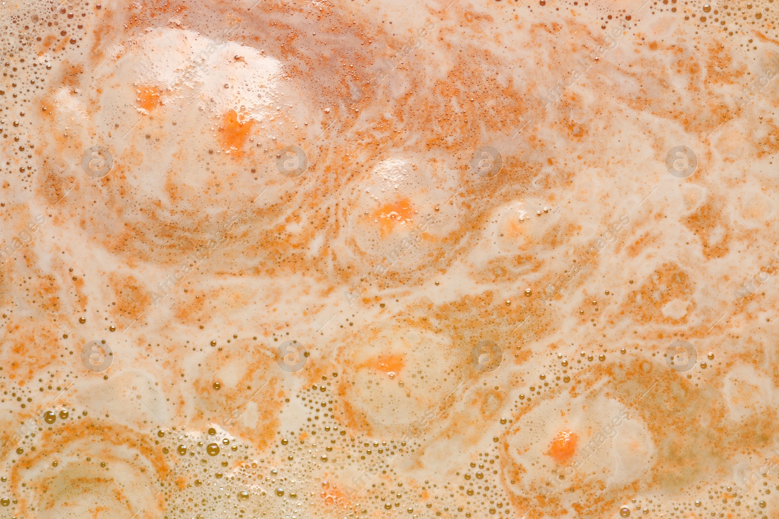 Photo of Colorful foam after dissolving bath bomb in water, closeup