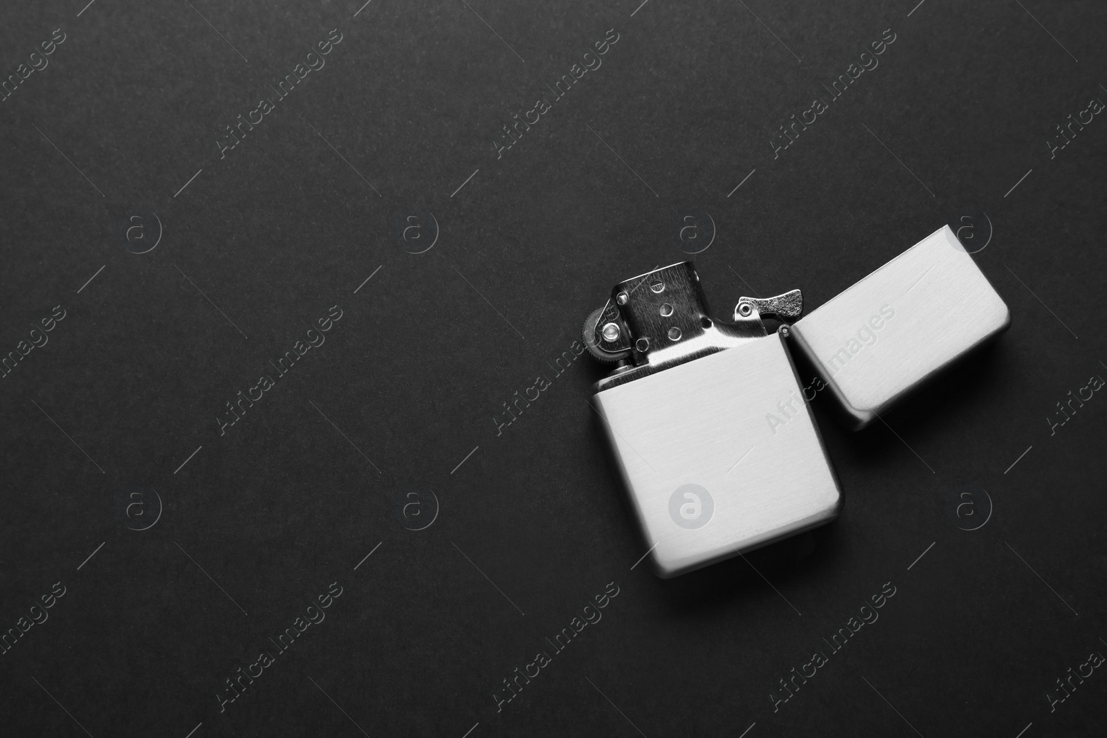Photo of Gray metallic cigarette lighter on black background, top view. Space for text