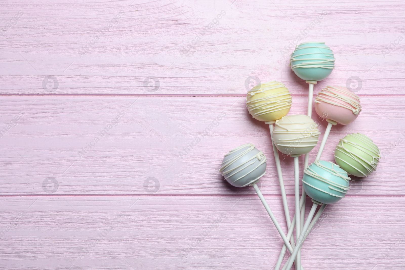 Photo of Sweet cake pops on pink wooden background, flat lay. Space for text