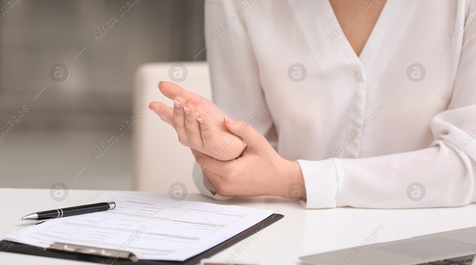 Photo of Young woman suffering from wrist pain in office