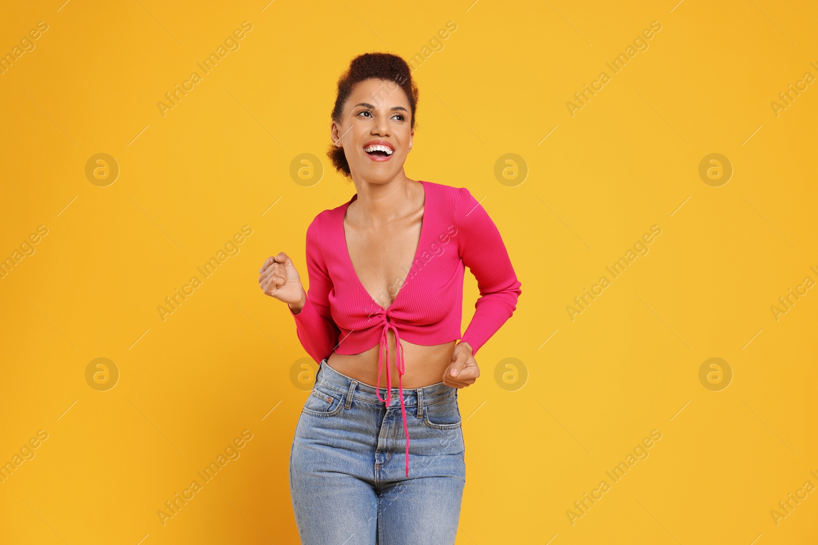 Photo of Happy young woman dancing on orange background