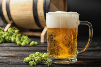 Photo of Composition with tasty beer and fresh green hops on wooden table. Space for text