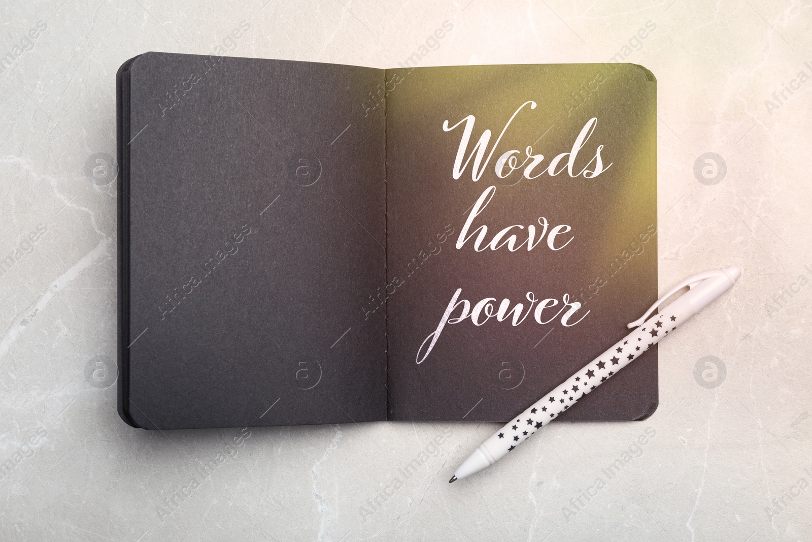 Image of Notebook with black pages and phrase Words Have Power on light grey marble table, top view