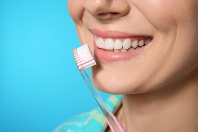 Woman with toothbrush on color background, closeup. Space for text