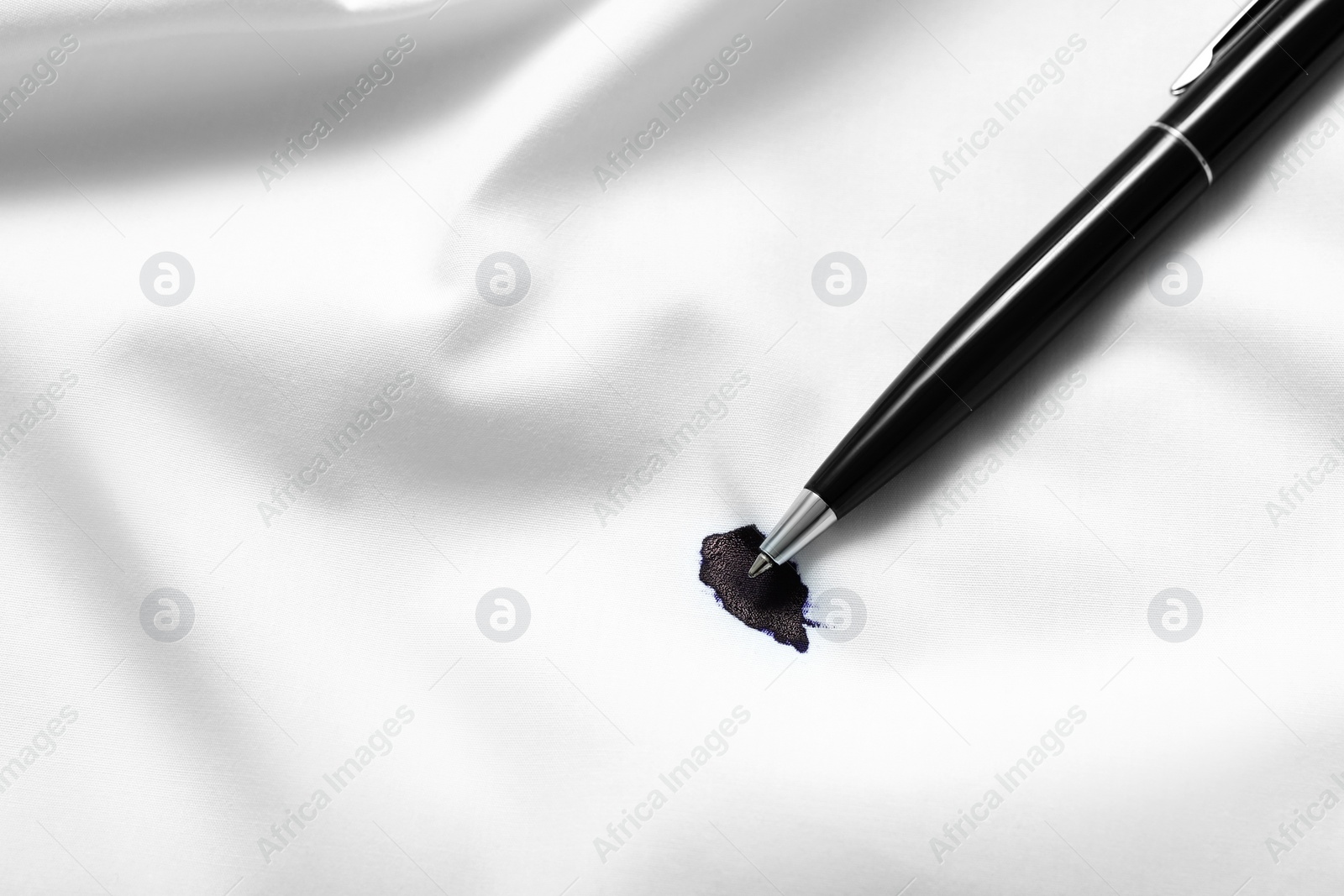 Photo of Pen and stain of black ink on white shirt, top view. Space for text