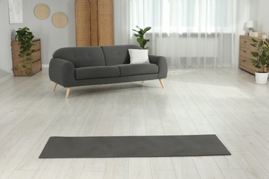 Grey yoga mat on floor in room
