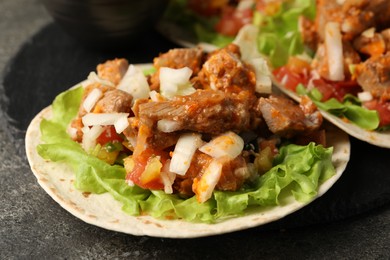 Photo of Delicious tacos with vegetables and meat on grey textured table, closeup