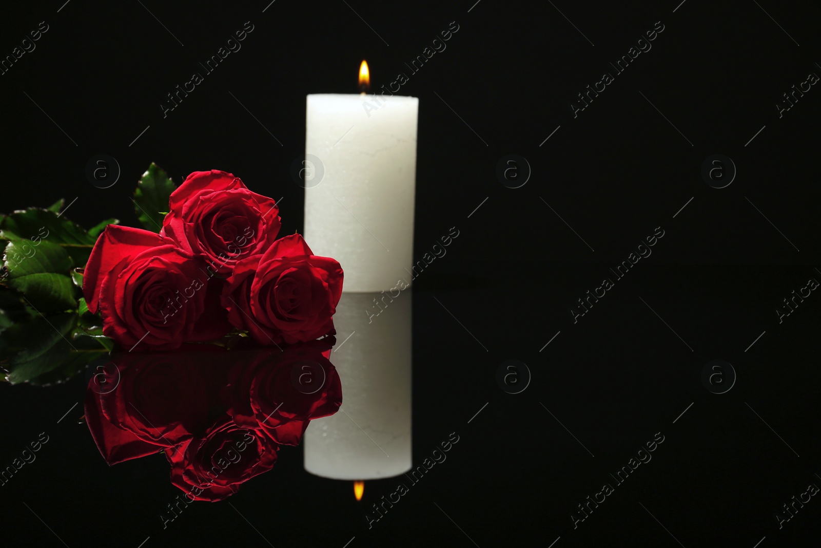 Photo of Beautiful red roses and candle on black background. Funeral symbol