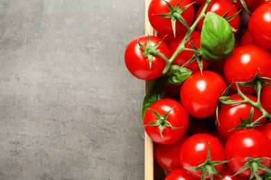 Photo of Crate with fresh cherry tomatoes on stone background, top view. Space for text