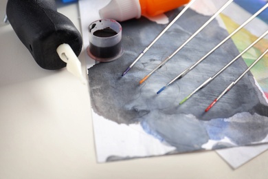 Photo of Tattoo machine, needles, ink and sheets of paper on table