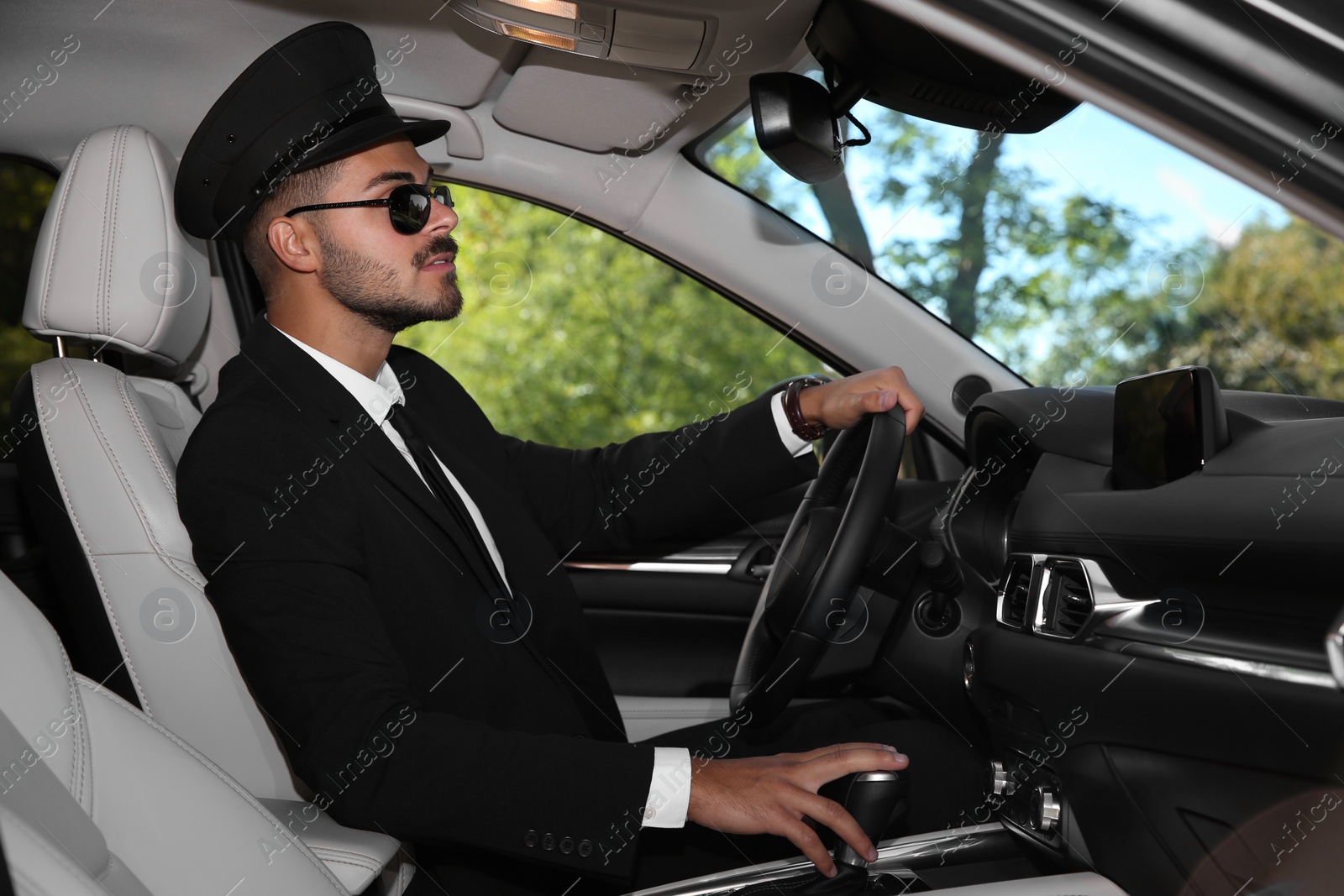 Photo of Young handsome driver in luxury car. Chauffeur service