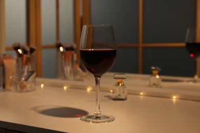 Glass of red wine on white table indoors