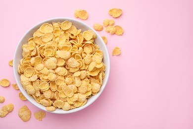 Photo of Breakfast cereal. Tasty corn flakes in bowl on pink table, top view. Space for text